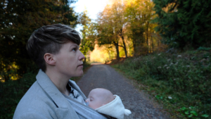 cat with her baby in the new forest. Green trees and the sun behind the trees in the background.