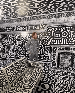 Mr Doodle standing in his house with the walls decorated by his doodles